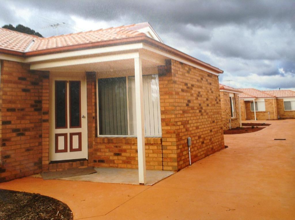 a brick house with a white door on a street at Melton Apartments in Melton