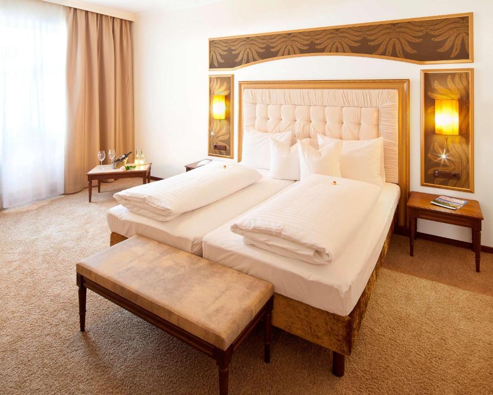 a large bedroom with two beds and a large headboard at BEST WESTERN Plus Hotel Goldener Adler Innsbruck in Innsbruck
