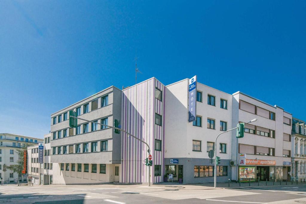 ein großes weißes Gebäude an einer Stadtstraße mit Ampeln in der Unterkunft Best Western City Hotel Pirmasens in Pirmasens