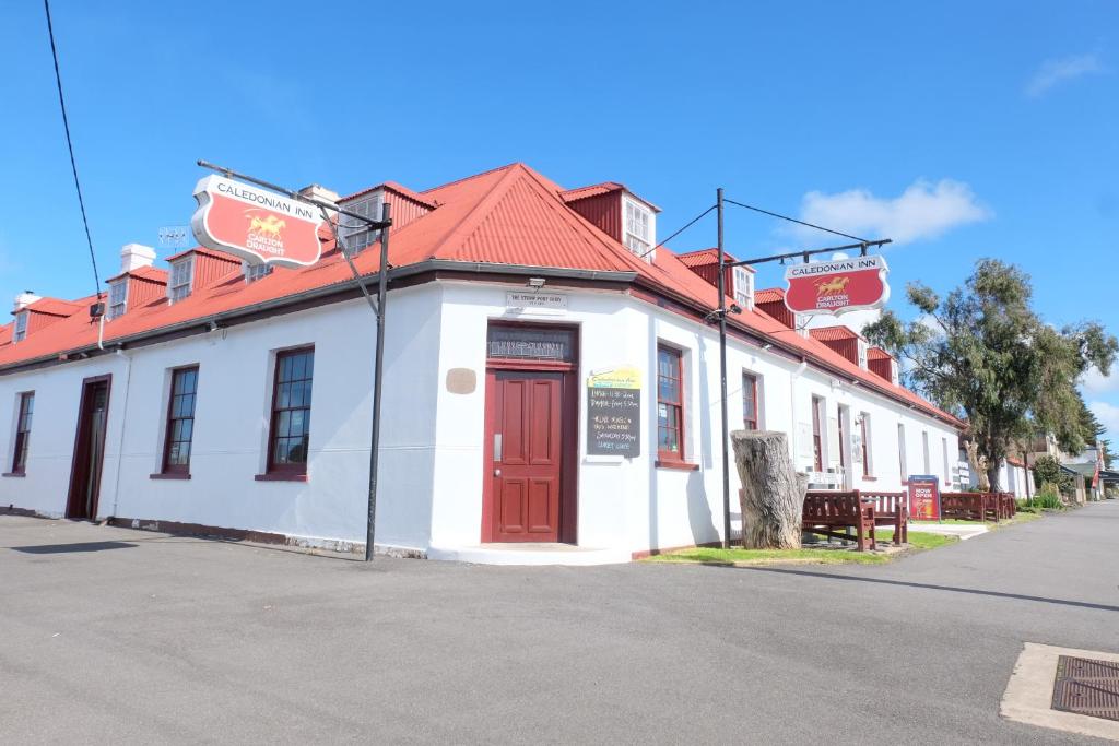 a white building with a red roof on a street at The Caledonian Inn in Port Fairy