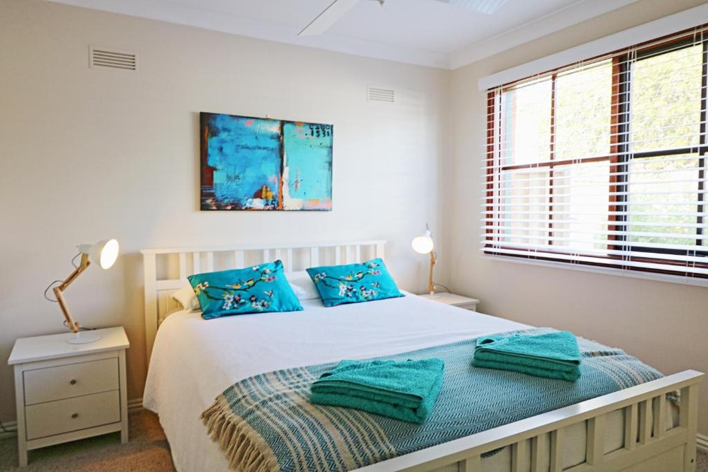 una camera da letto con letto e cuscini blu di Jodi's Beach Retreat Eden a Eden