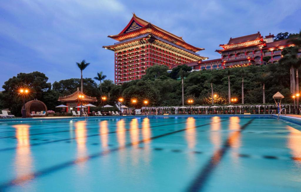 
a large swimming pool in front of a large building at The Grand Hotel in Taipei
