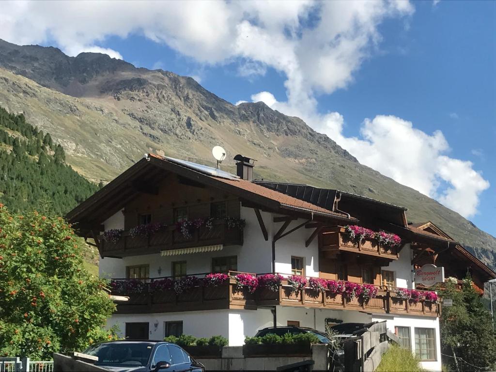 ein Gebäude mit Blumen auf den Balkonen und einem Berg in der Unterkunft Appartment Venter Bergwelt in Vent