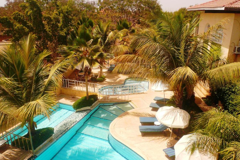 - une vue sur la piscine bordée de palmiers dans l'établissement Les Flamboyants, à Saly Portudal