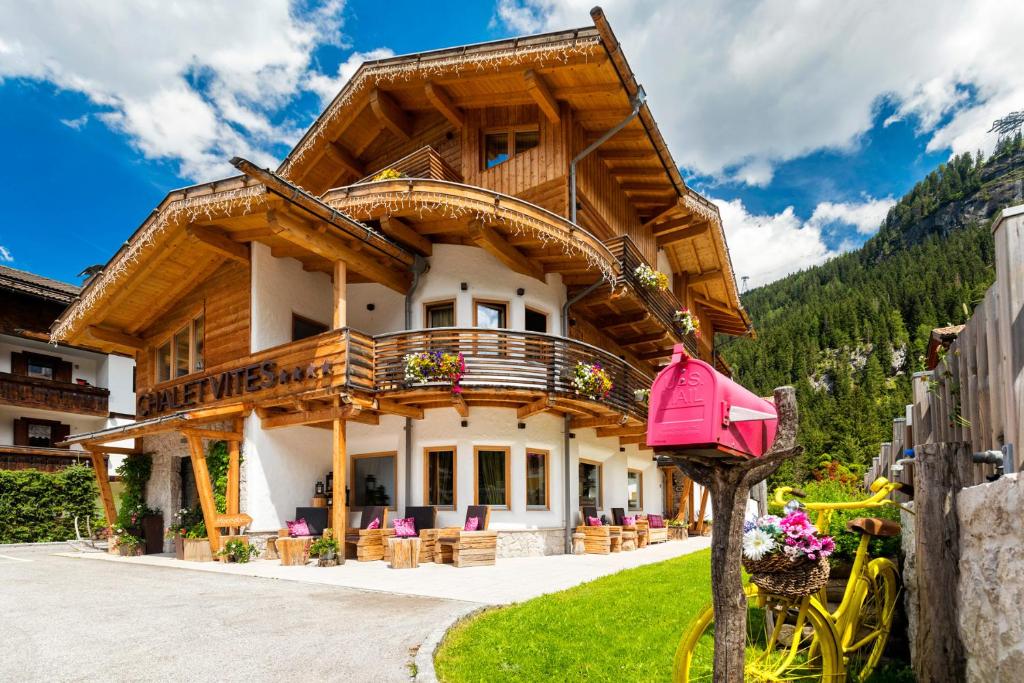 uma casa nas montanhas com uma varanda em Chalet Vites Mountain Hotel em Canazei