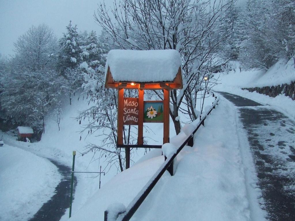 un cartel cubierto de nieve junto a una carretera cubierta de nieve en Agriturismo Maso Santa Libera, en Tesero