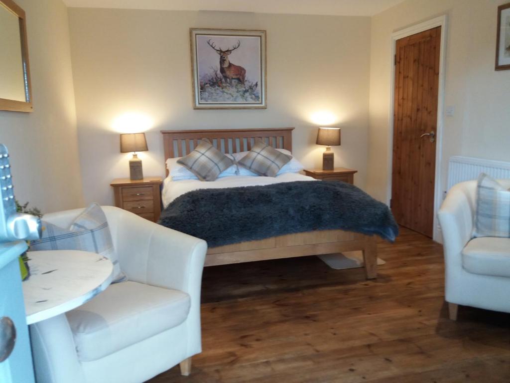 a bedroom with a bed and a couch and two chairs at The Stables - Deer Park Farm in Solihull