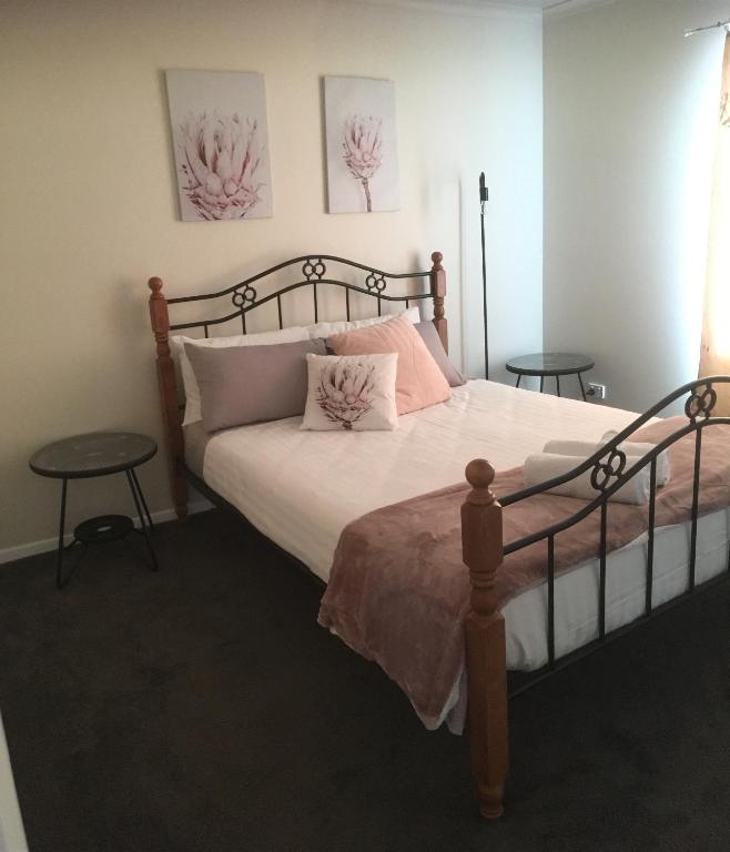 a bedroom with a bed with pink pillows and two tables at 3ree- Spacious & Charming Apartment in Devonport