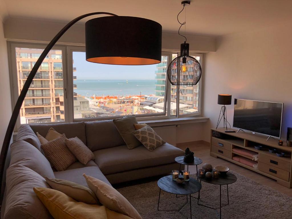 a living room with a couch and a large window at Appartement Seaview Bunnenplein in Knokke-Heist