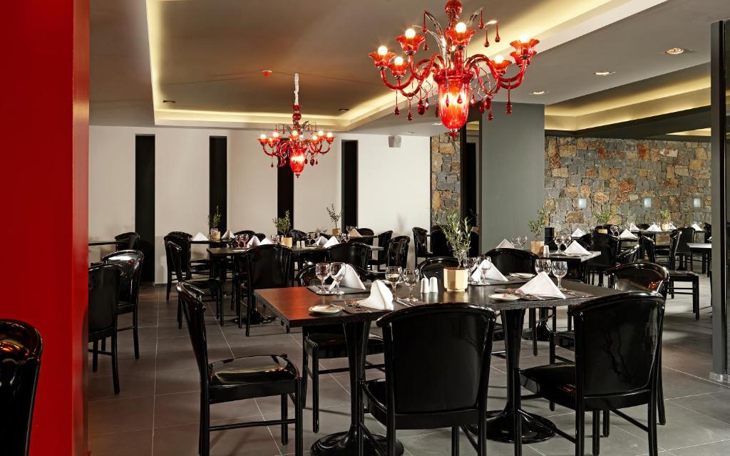 a dining room with tables and chairs and a chandelier at Out Of The Blue Resort & Spa in Agia Pelagia