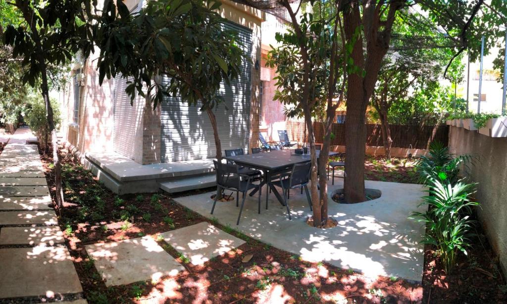 un patio con mesa y sillas bajo un árbol en Ruth Suite en Jerusalén