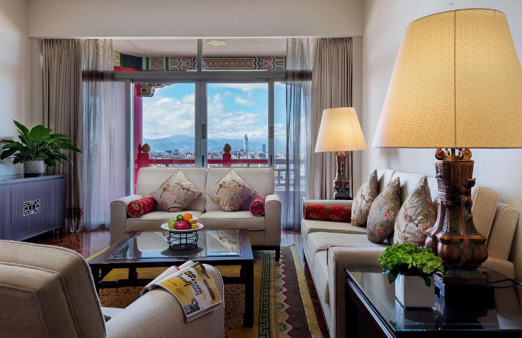 a living room with couches and a large window at The Grand Hotel in Taipei