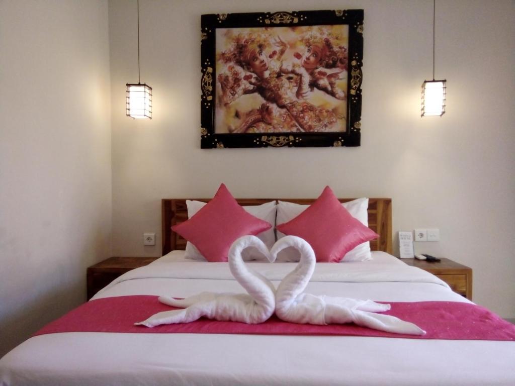 two white swans making a heart on a bed at Wisna House in Sanur