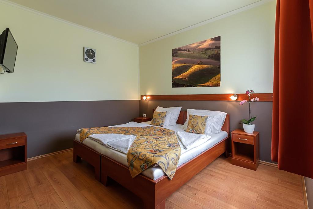 um quarto com uma cama e um quadro na parede em Aranypatkó Fogadó-Étterem em Győrújbarát