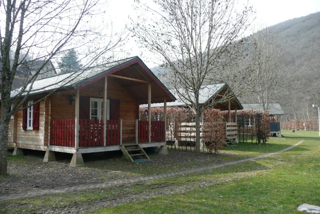 uma pequena cabina de madeira com uma cerca vermelha num campo em Dirbach Plage Parc em Dirbach