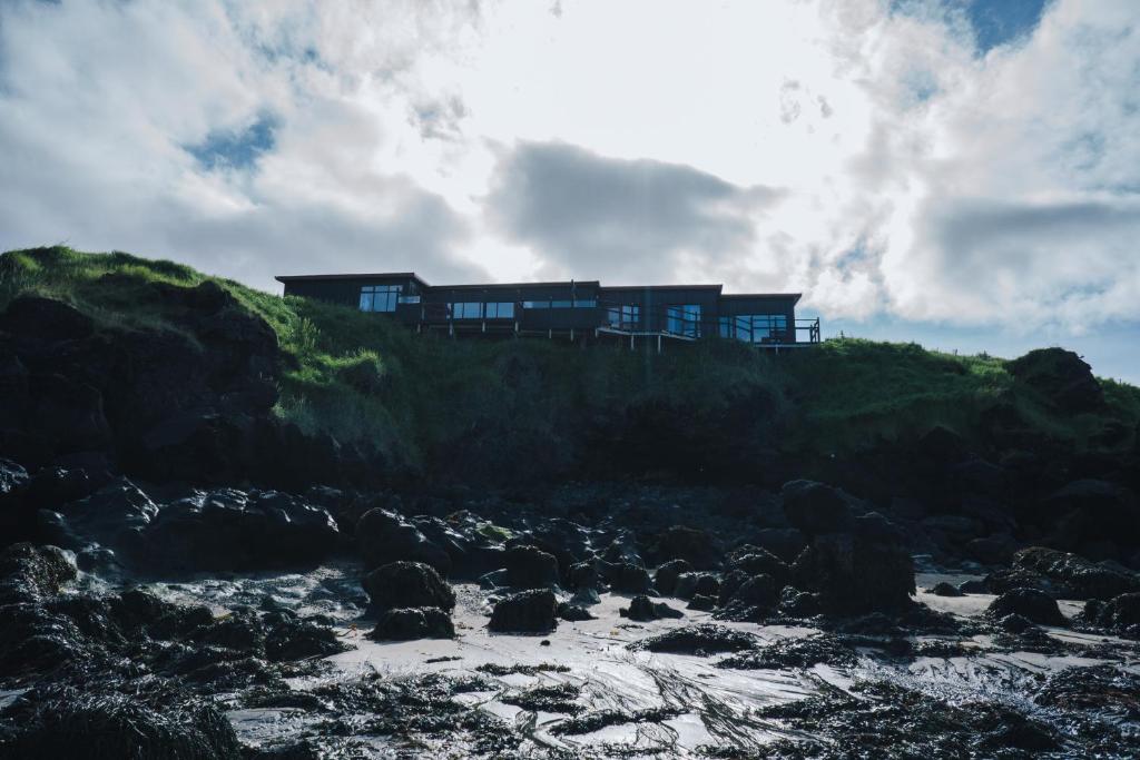 ein Haus auf einem Hügel neben einem Strand in der Unterkunft Kleifar: Ocean View Apartment in Hellissandur