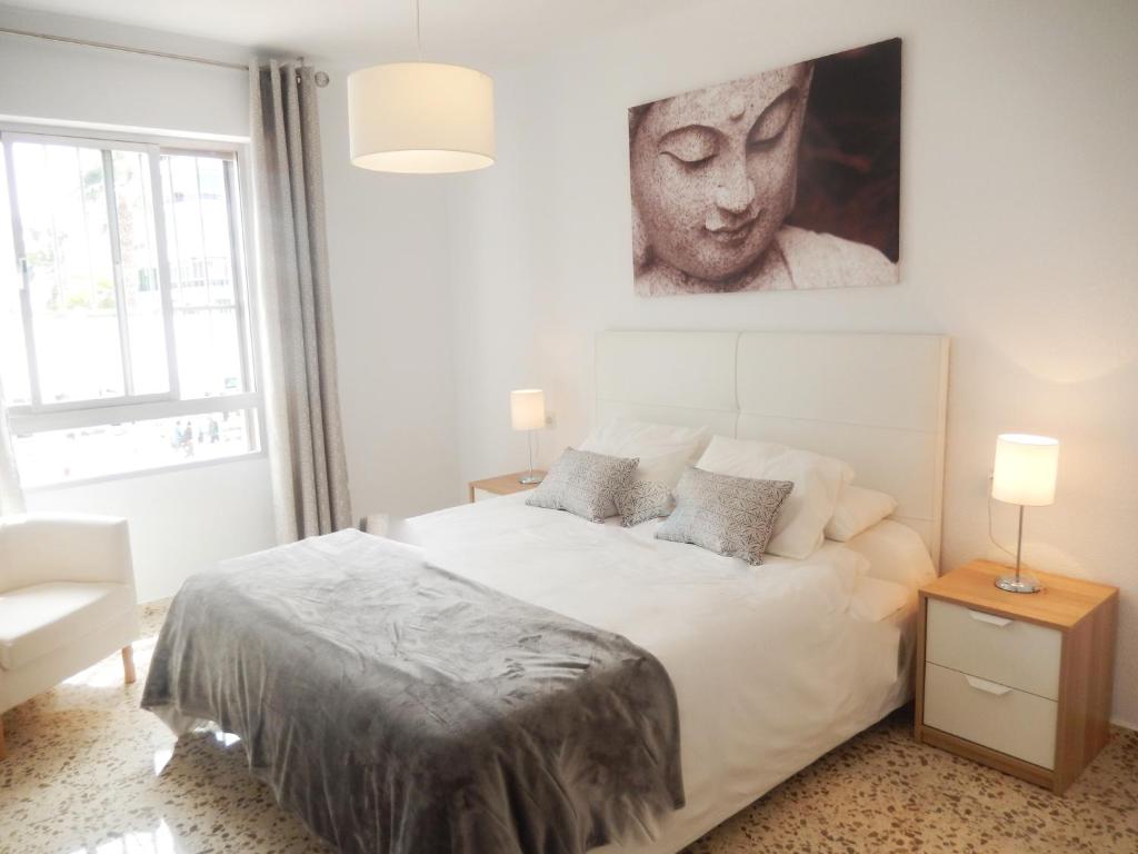 トレ・デル・マールにあるCasa Rosaの白いベッド1台、壁に肖像画が備わるベッドルーム1室が備わります。