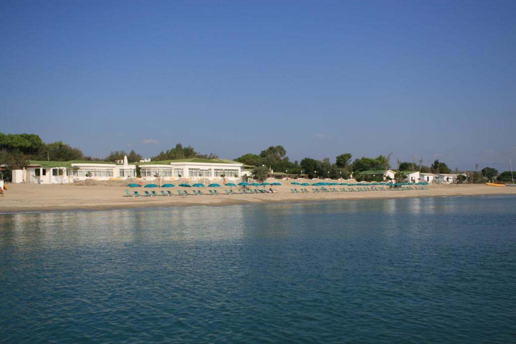 una playa con sillas y sombrillas junto al agua en Hotel Club Poseidon, en Stalettì