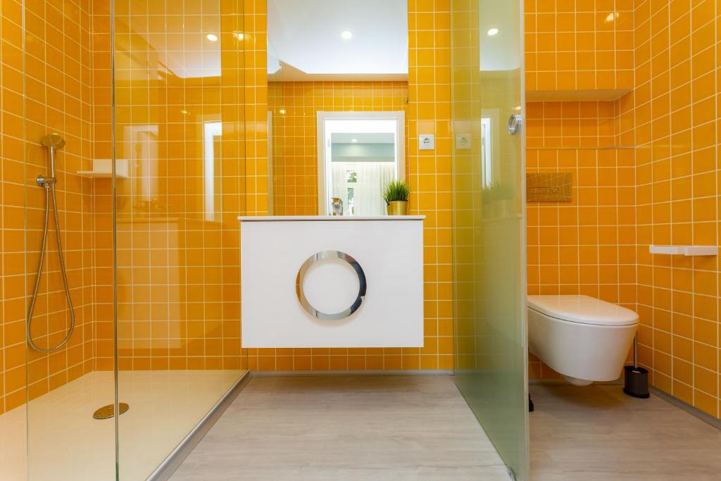 a bathroom with a shower and a toilet and yellow tiles at Chic Studios in Parede