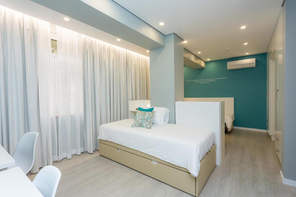 a bedroom with a white bed and a blue wall at Chic Studios in Parede
