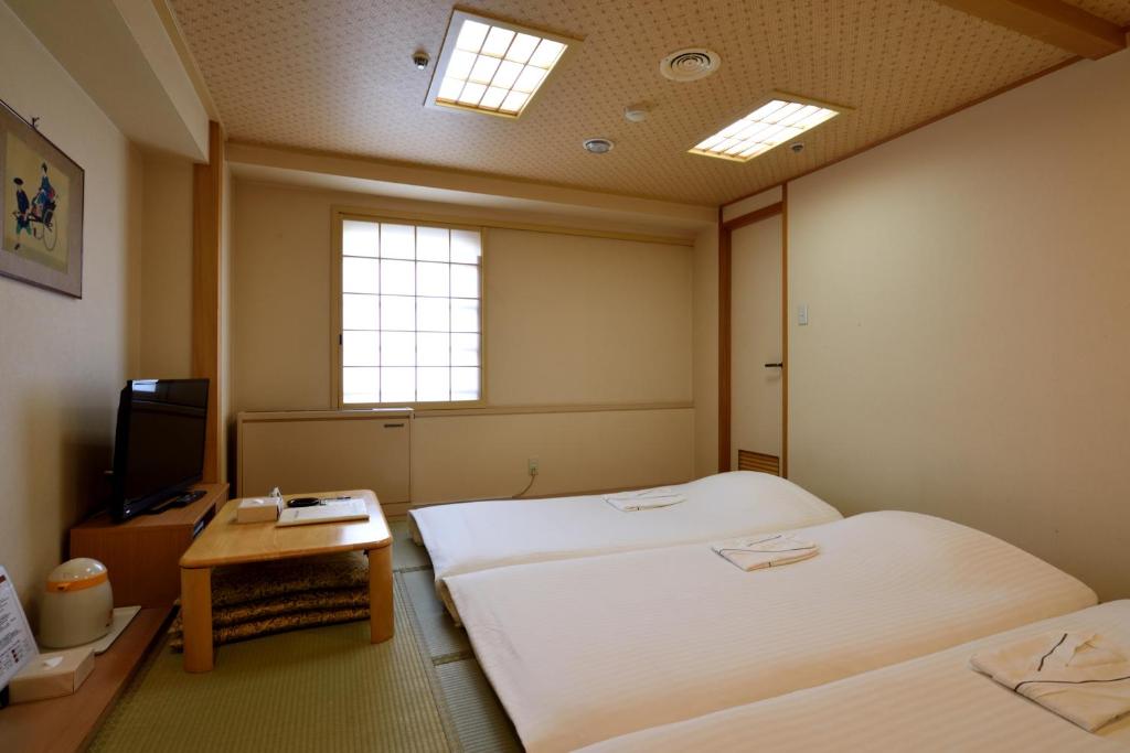 a hotel room with two beds and a television at Hotel Johzenji in Sendai