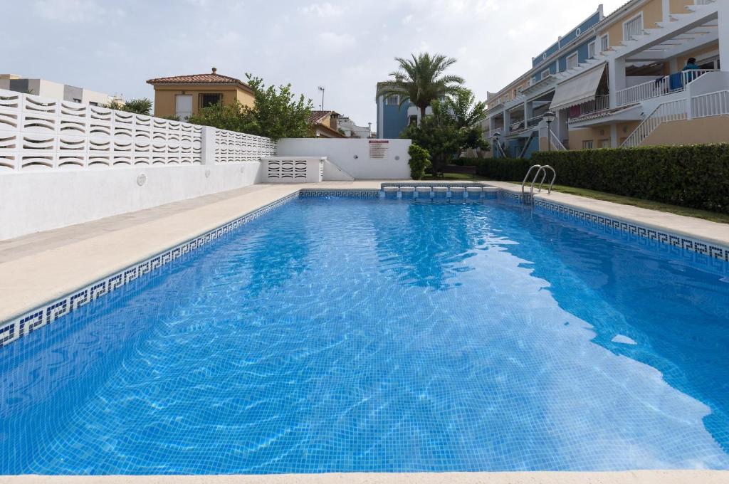 a swimming pool with blue water in front of a building at Golden in Playa de Gandia