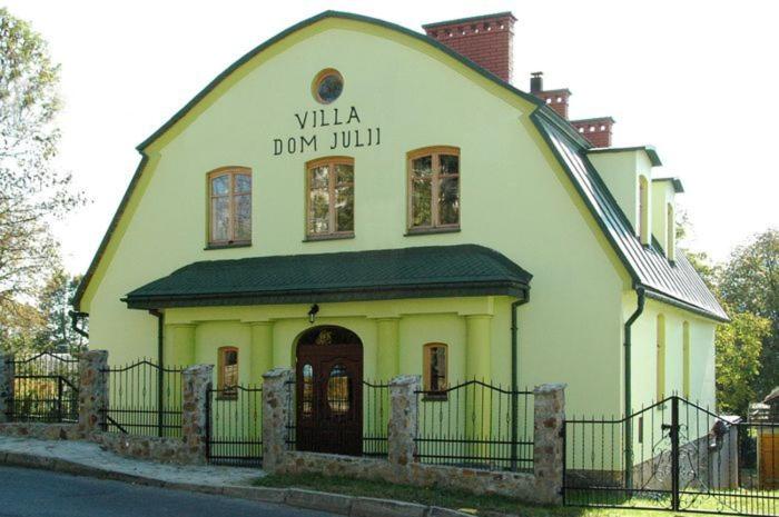 un bâtiment jaune et blanc avec un toit noir dans l'établissement Villa Dom Julii, à Sanok