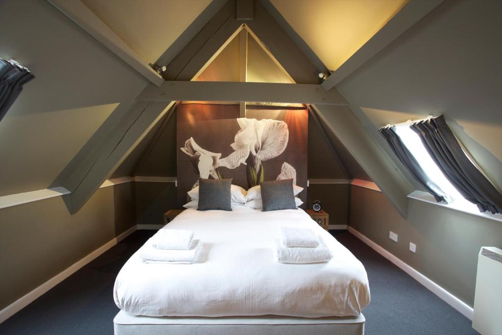 um quarto com uma grande cama branca num sótão em The Kings Arms em Didmarton