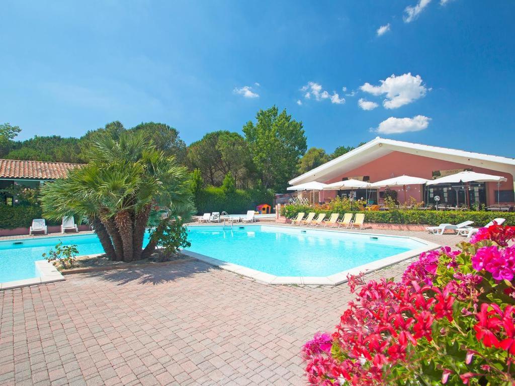 a patio area with a pool, chairs, and patio furniture at Camping Village Il Gineprino in Marina di Bibbona