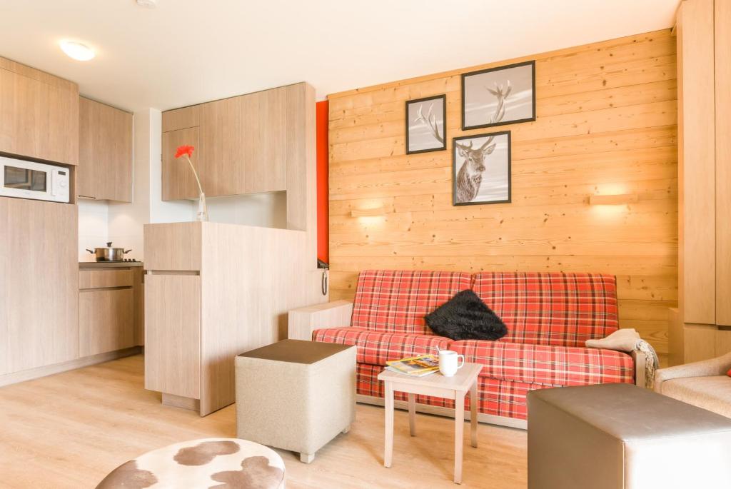 a living room with a red couch and a kitchen at Résidence Pierre & Vacances Atria-Crozats in Avoriaz