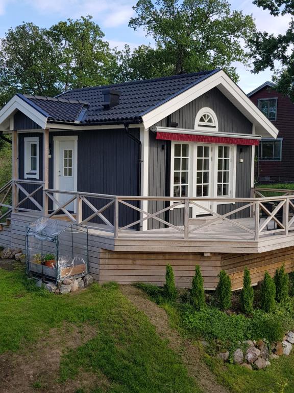 una casa con una gran terraza y una casa en Toppstugan en Åkerö