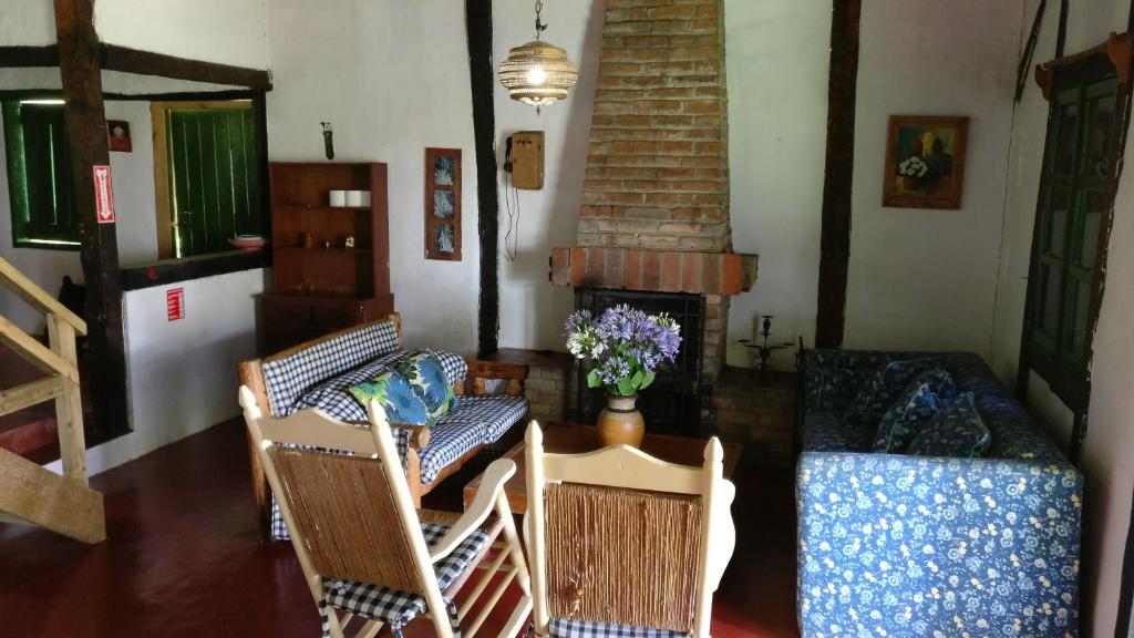 een woonkamer met een bank en stoelen en een open haard bij Villa Pajon Eco Lodge in Constanza