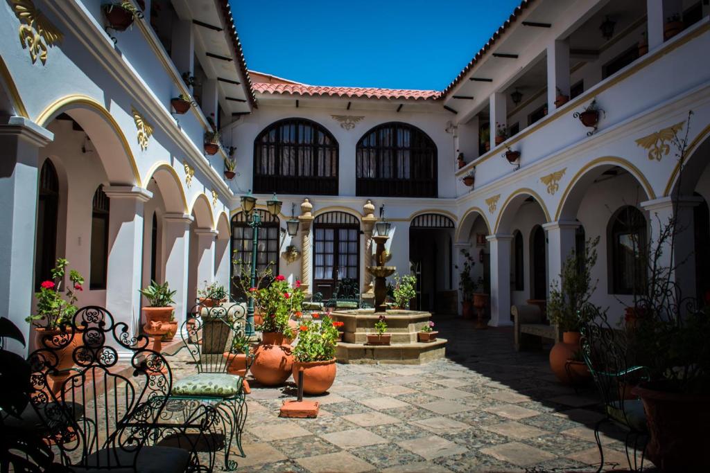 a courtyard with chairs and potted plants in a building at Hostal Sucre in Sucre