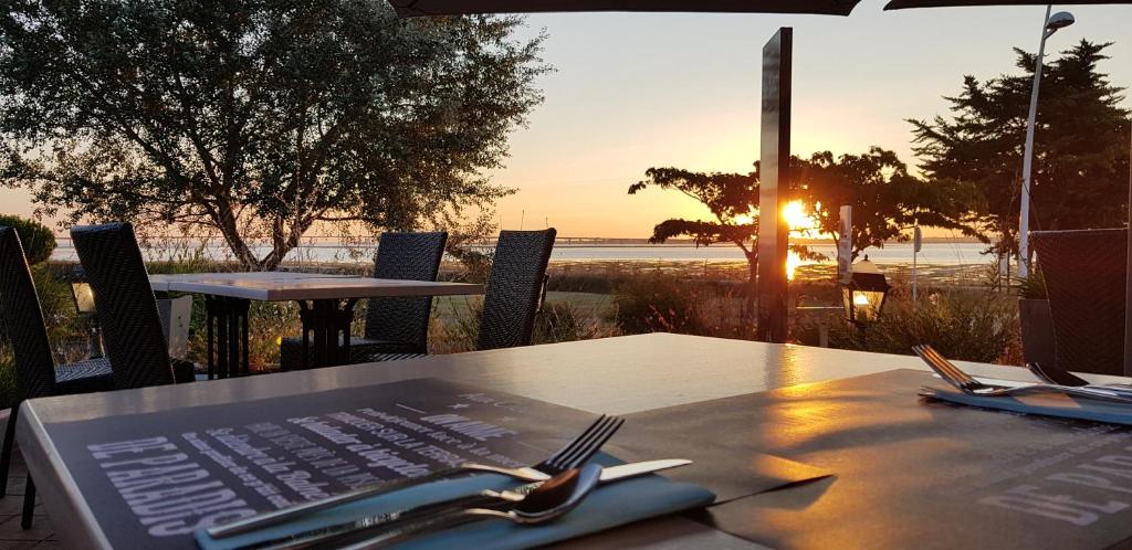 a table with a plate with fork and knife and the sunset at Hotel et Spa Les Cleunes Oléron in Saint-Trojan-les-Bains