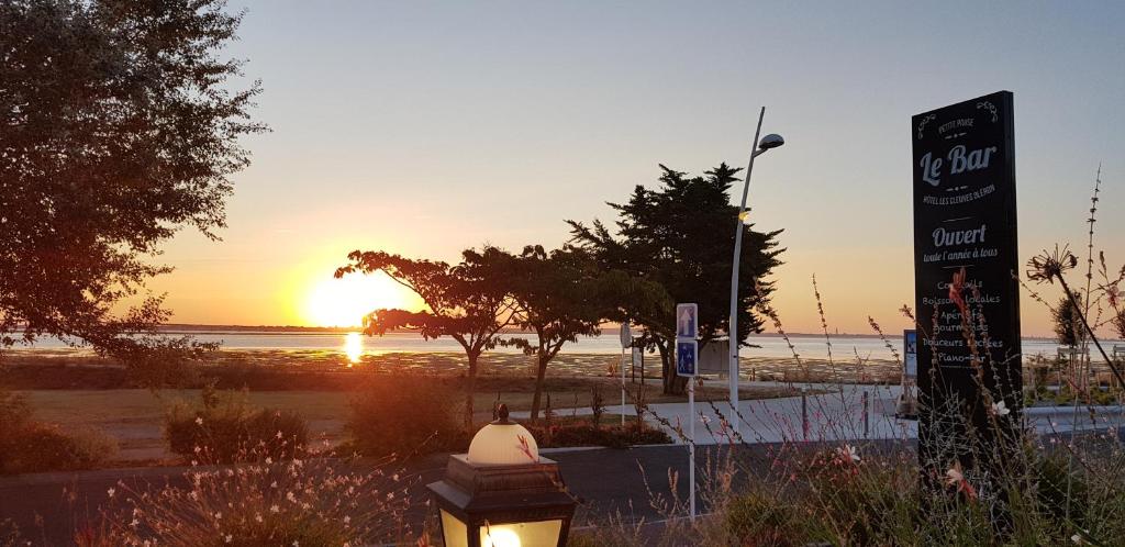 a sunset at the beach with a sign and a sign at Hotel et Spa Les Cleunes Oléron in Saint-Trojan-les-Bains