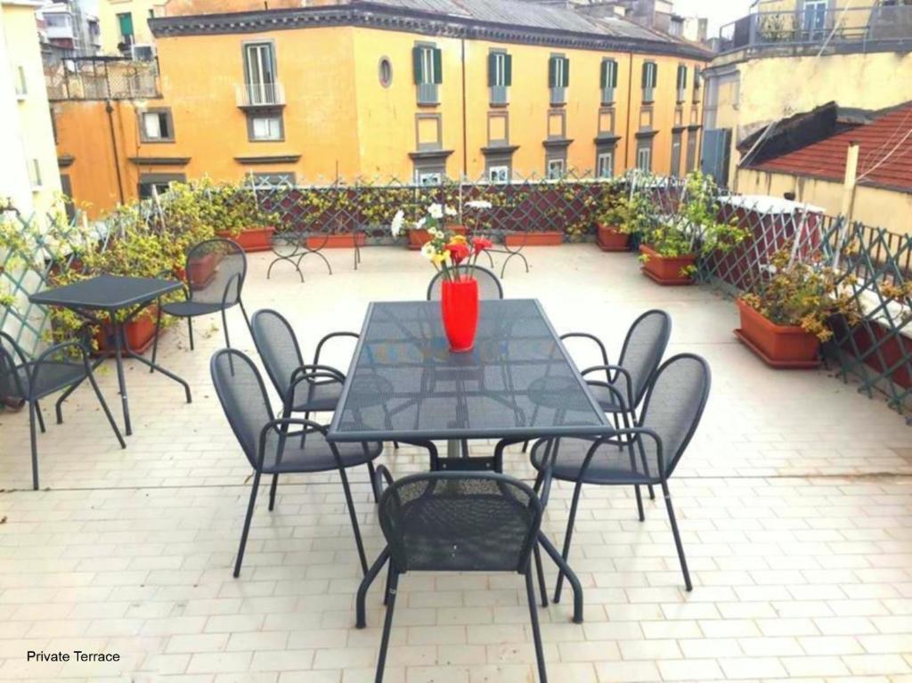 ナポリにあるPanoramico con terrazzoのテーブルと椅子、花瓶のあるパティオ