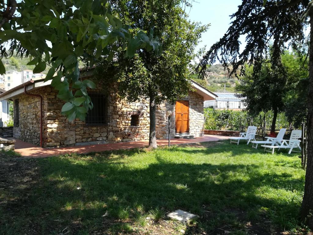 a stone cottage with a patio and a yard at Fontanacota in Imperia