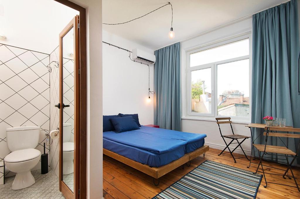 een kleine slaapkamer met een blauw bed en een raam bij Generaator Sofia in Sofia