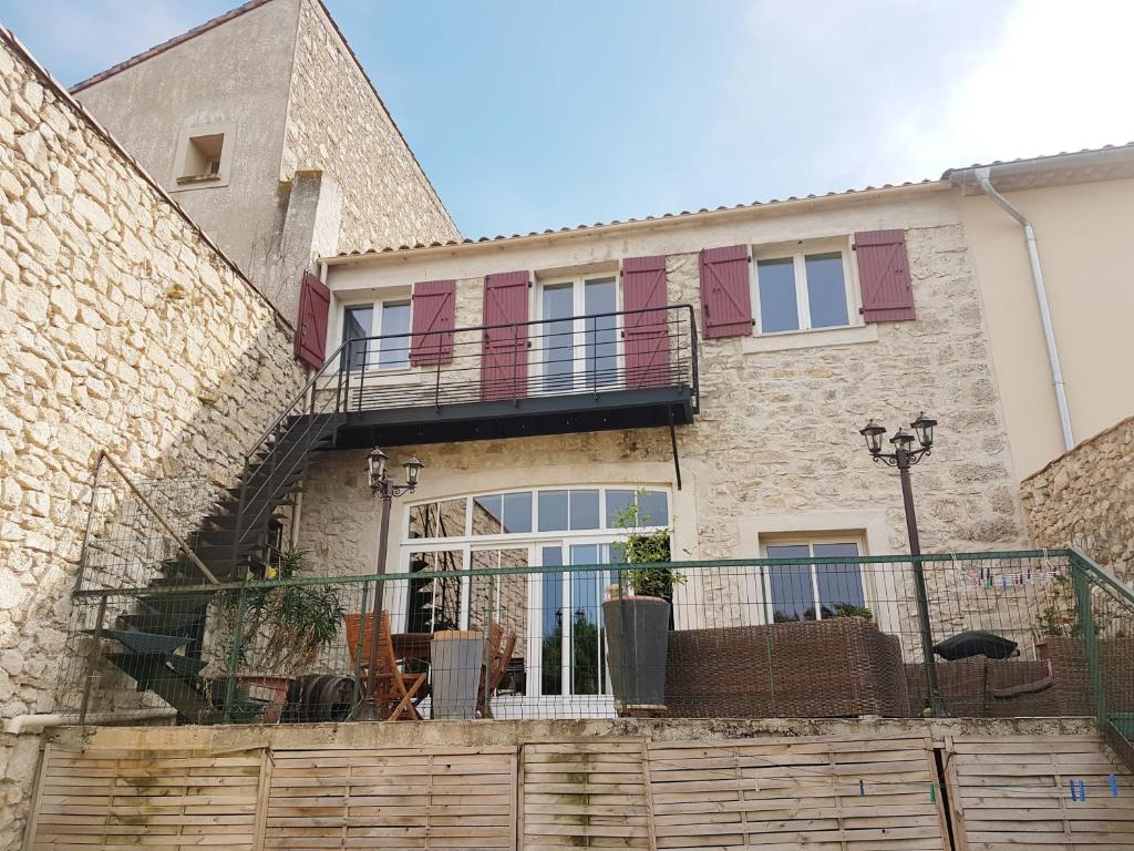 ein Backsteinhaus mit einem Balkon und einer Terrasse in der Unterkunft La Barbacane in Sigean