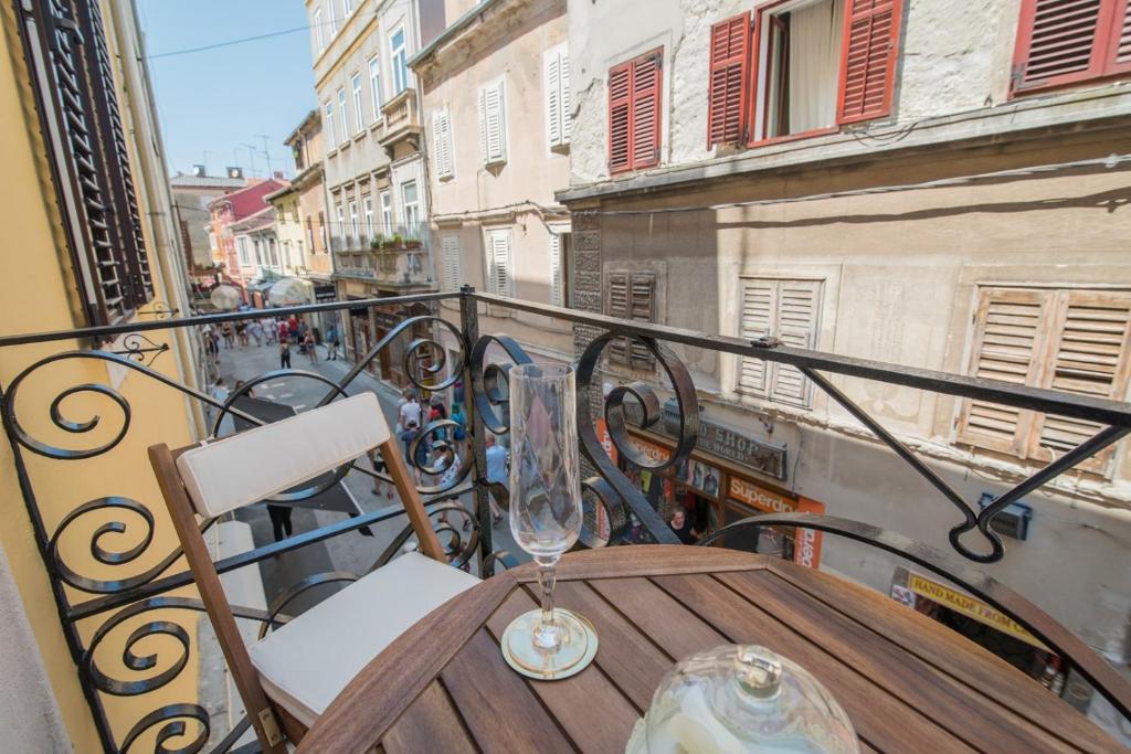 a wooden table on a balcony with a wine glass at Leona Deluxe Apartments in Pula