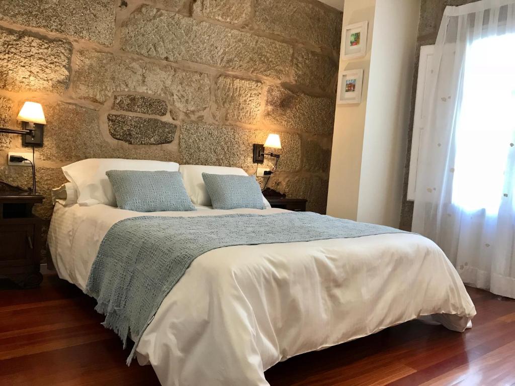 Sweet Home Pontevedra في بونتيفيدرا: غرفة نوم بسرير كبير وبجدار حجري