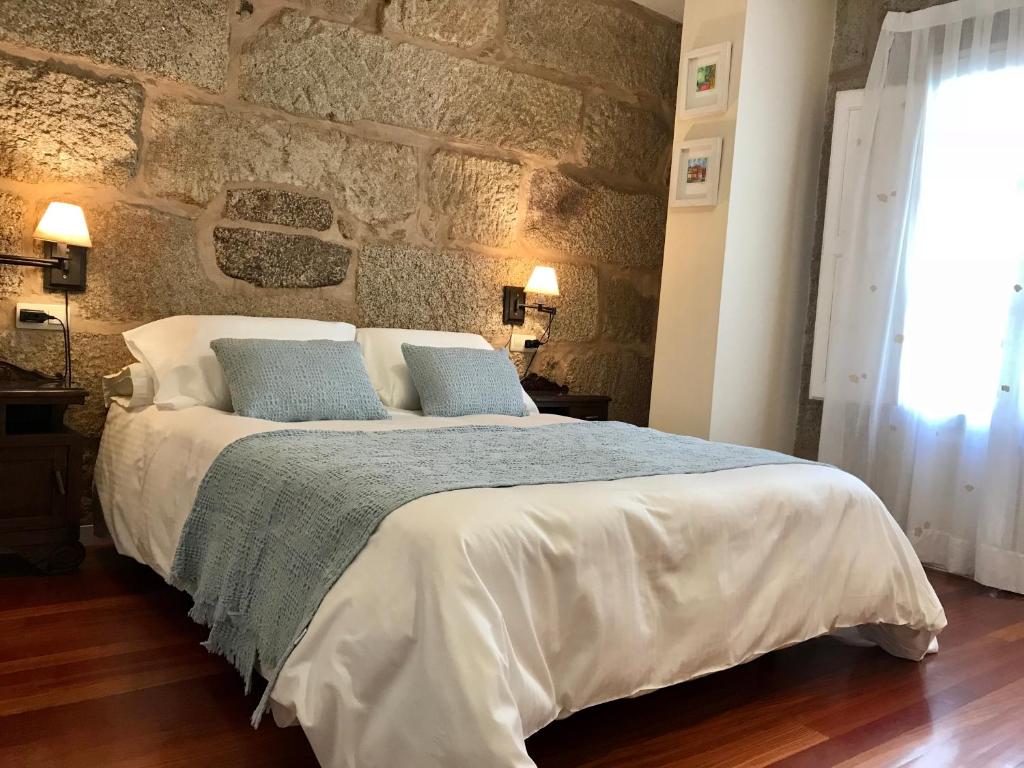 1 dormitorio con 1 cama grande y pared de piedra en Sweet Home Pontevedra, en Pontevedra