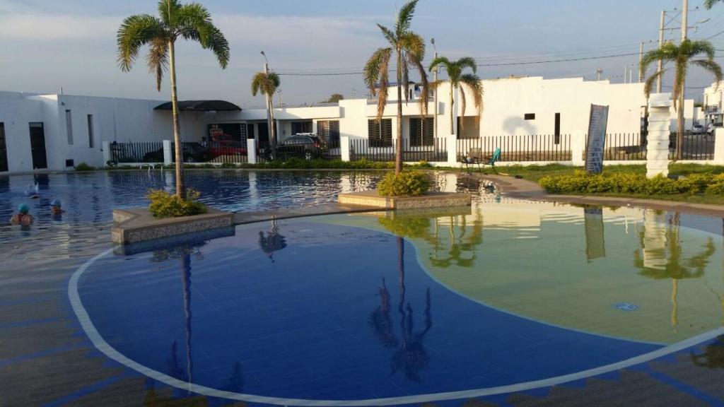 a swimming pool with palm trees and a building at Excelente Casa vacacional in Flandes