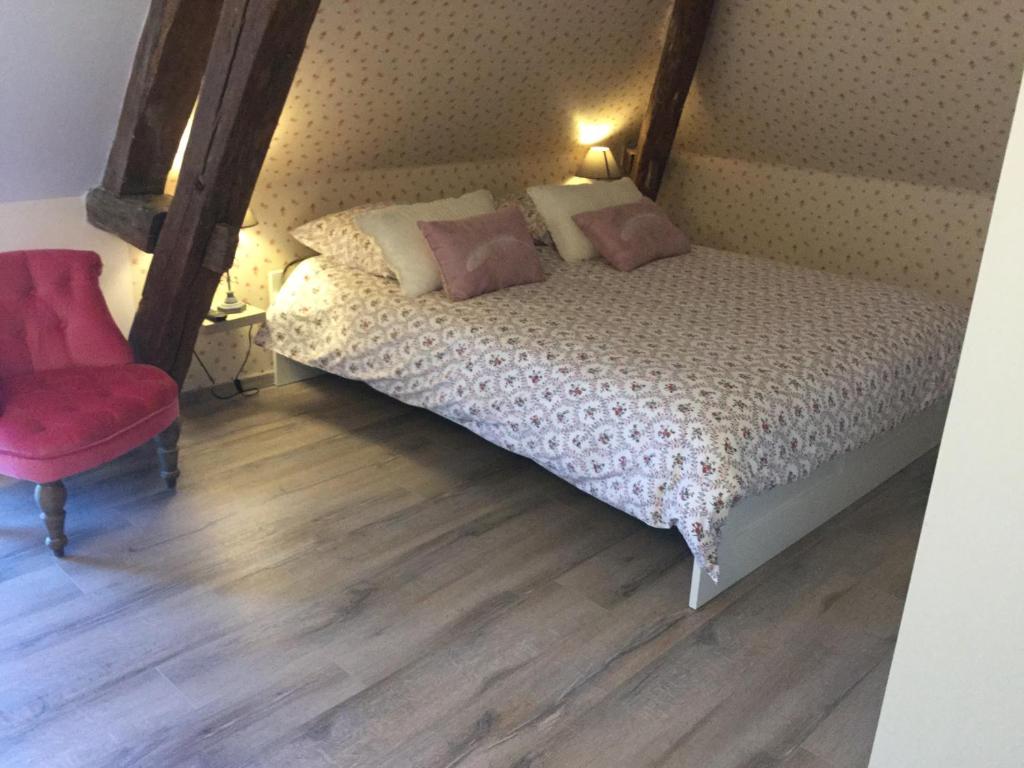 um quarto com uma cama e uma cadeira vermelha em La Ressource em Fontguenand
