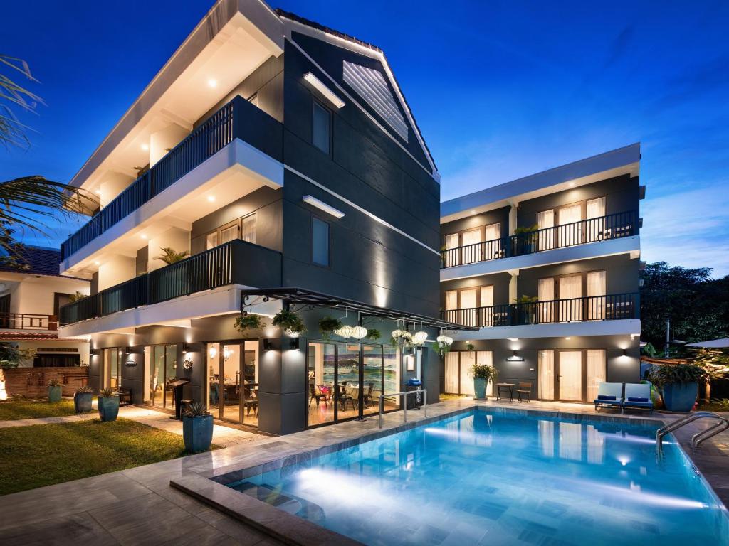 una vista exterior de un edificio con piscina en The Blue Alcove Hotel en Hoi An