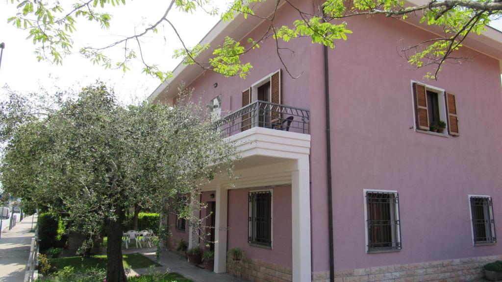 un edificio rosa con balcón y un árbol en casa vacanze sweet home, en San Giovanni in Marignano
