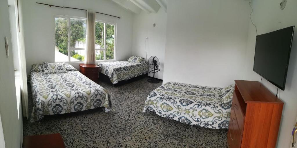 um quarto com 2 camas e uma televisão de ecrã plano em Hotel Villa Amparo em Chinauta