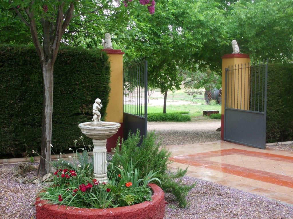 a fountain in a garden with a gate and flowers at Casa Rural Villa Rosa in Écija