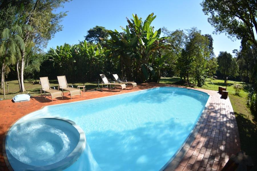 uma piscina num quintal com cadeiras e árvores em Iguassu Eco Hostel - IguassuEcoHostel - Eco Suítes em Foz do Iguaçu