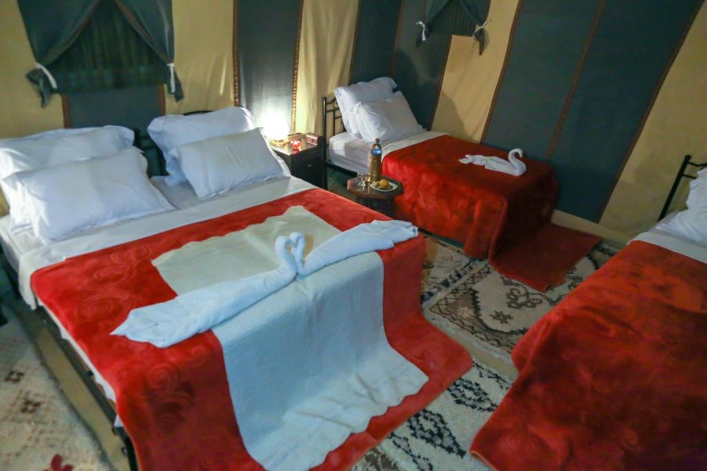 a hotel room with two beds with towels on them at Sahara Desert Luxury Camp in Merzouga